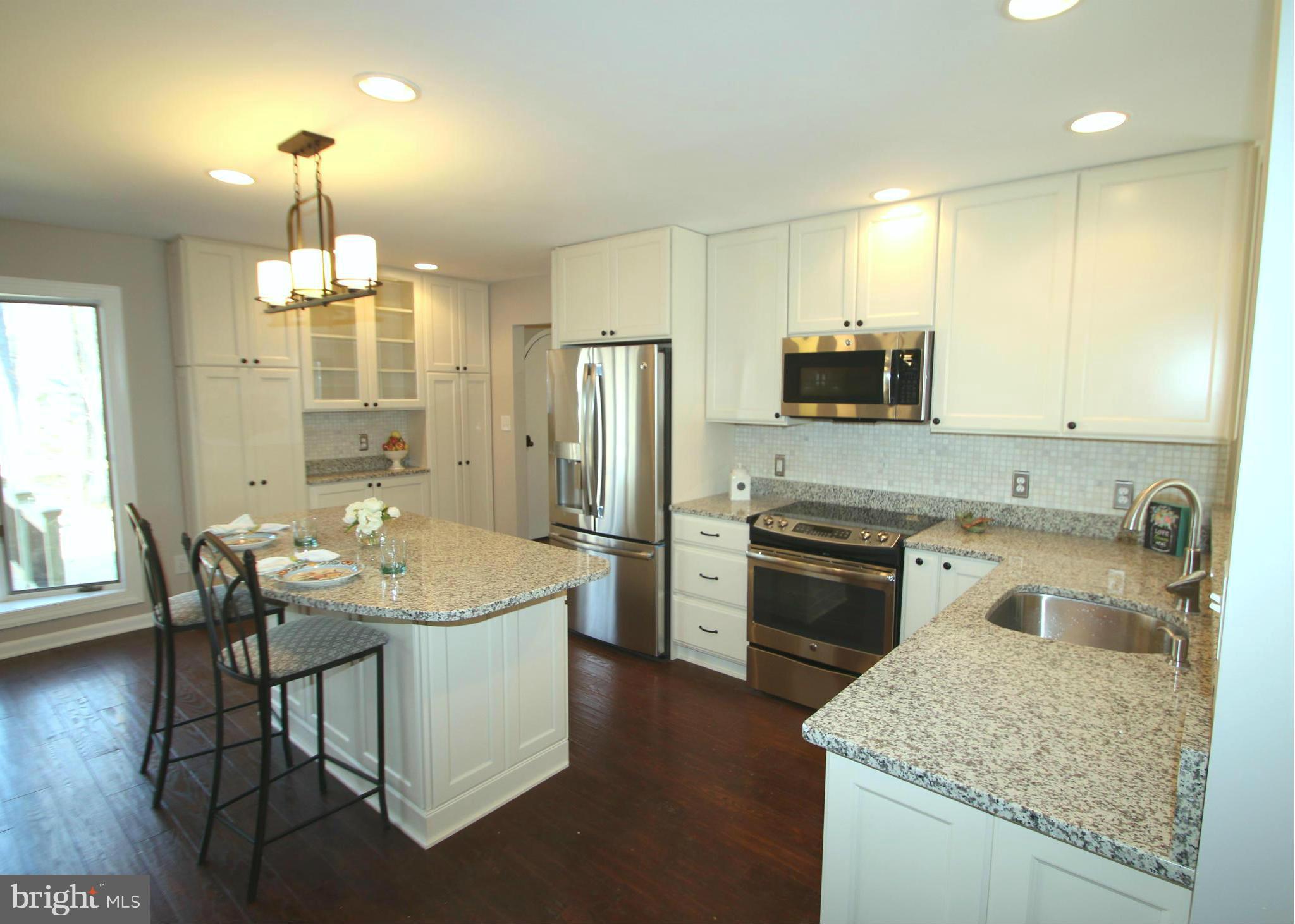4321 Oaktree Road Rockville, MD 20853 - Photo 3 of 24 a kitchen with a sink a kitchen island with wooden cabinets and stainless steel appliances