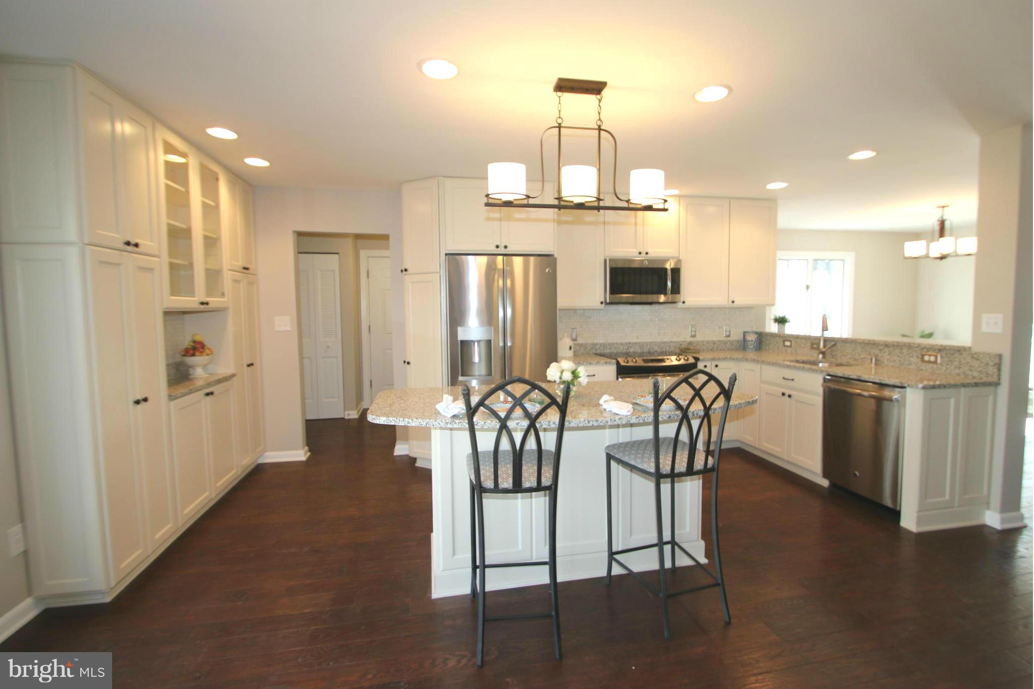 4321 Oaktree Road Rockville, MD 20853 - Photo 4 of 24 a kitchen with stainless steel appliances kitchen island granite countertop a refrigerator a stove a sink a dining table and chairs with wooden floor