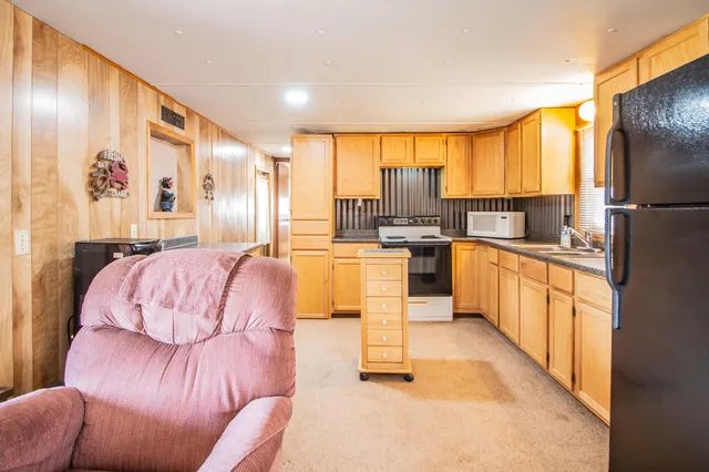 a large kitchen with stainless steel appliances kitchen island granite countertop a couch and a view of living room