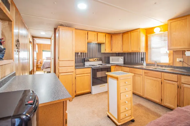 a view of a kitchen with kitchen island a large window cabinets a sink and stainless steel appliances