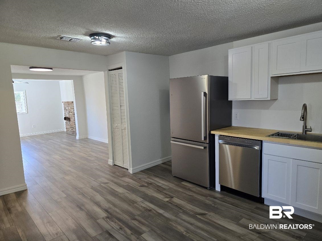 821 Dailey Street Brewton, AL 36426 - Photo 12 of 17 Kitchen featuring white cabinets, stainless steel appliances, a textured ceiling, and dark wood-style floors