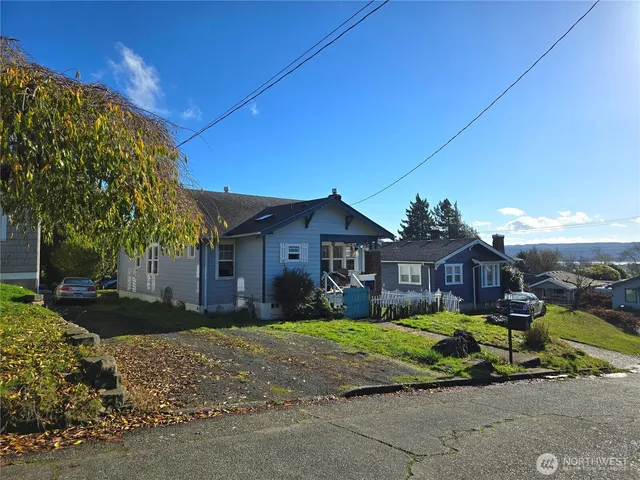 a view of a house with a big yard and large tree