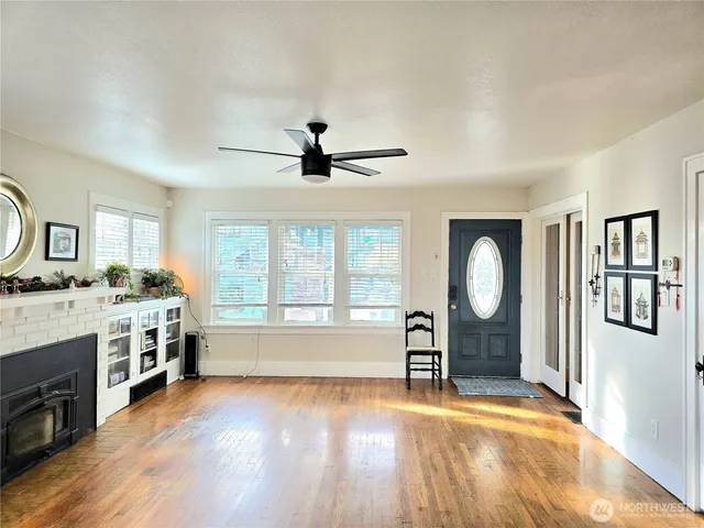 a living room with stainless steel appliances granite countertop a stove a sink a refrigerator cabinets and a dining table with wooden floor