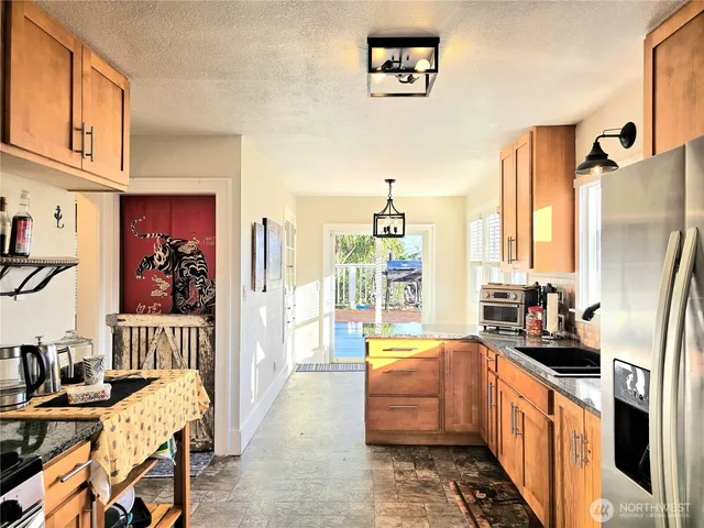 a large kitchen with stainless steel appliances a stove a refrigerator a dining table and chairs with wooden floor