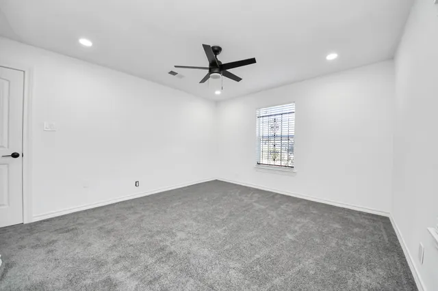 an empty room with windows and fan