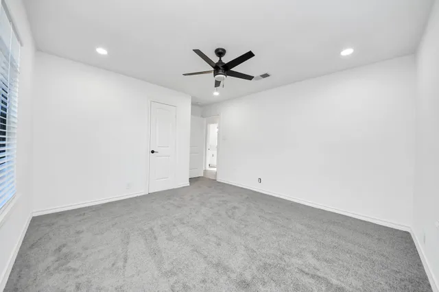 an empty room with a ceiling fan and a window