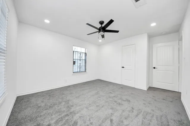 a view of a livingroom with a ceiling fan & windows