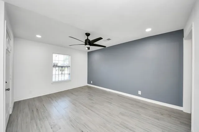 a view of an empty room with a window and wooden floor