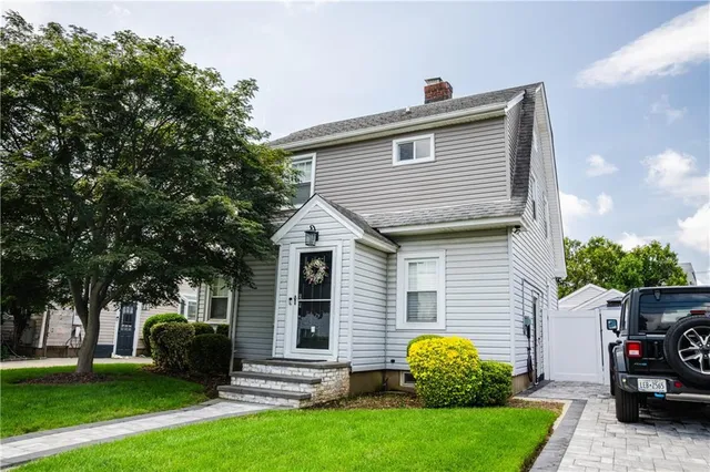 a view of a white house with a yard and large tree