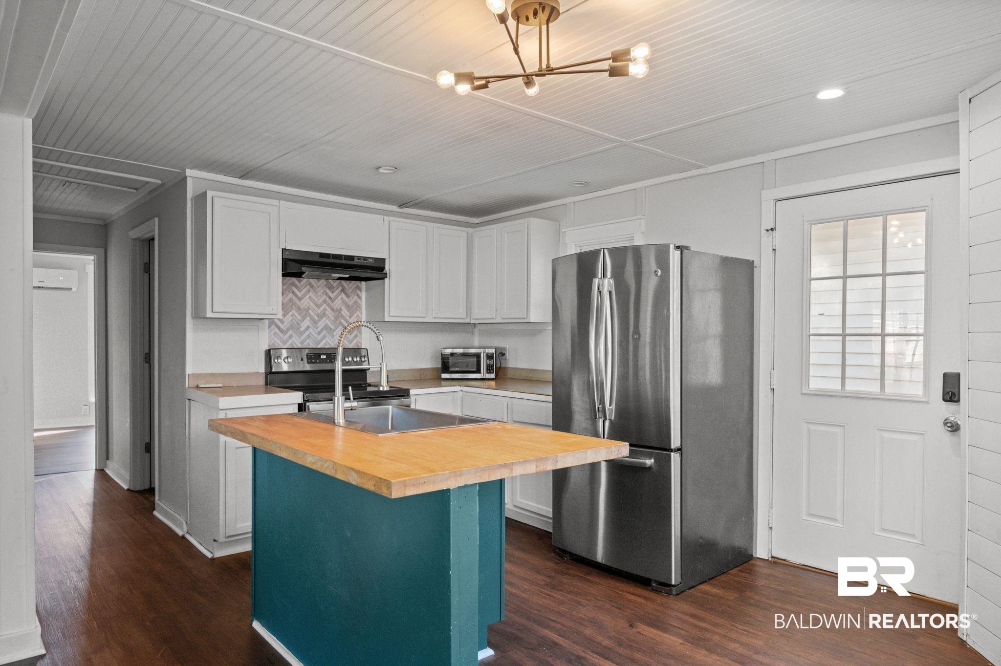 503 North Holly Street Foley, AL 36535 - Photo 4 of 23 Kitchen with appliances with stainless steel finishes, dark hardwood / wood-style flooring, white cabinets, ornamental molding, and a center island with sink