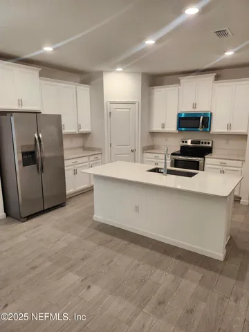 a kitchen with stainless steel appliances a refrigerator sink and microwave
