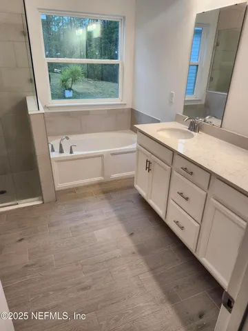a bathroom with a double vanity sink a mirror and a bathtub