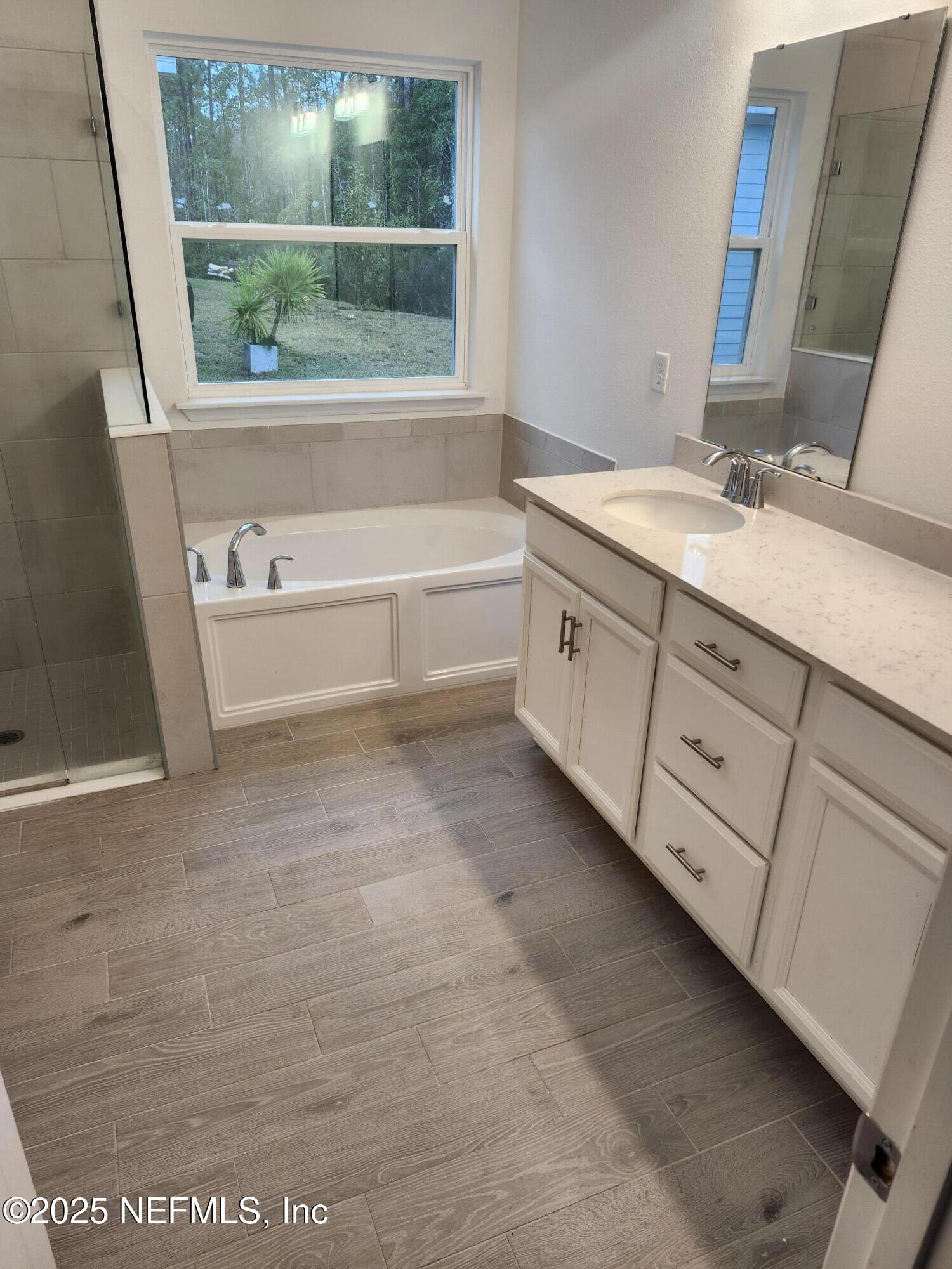 607 Lake Sinclair Street St. Augustine, FL 32084 - Photo 9 of 19 a bathroom with a double vanity sink a mirror and a bathtub