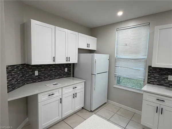 a kitchen with white cabinets and refrigerator