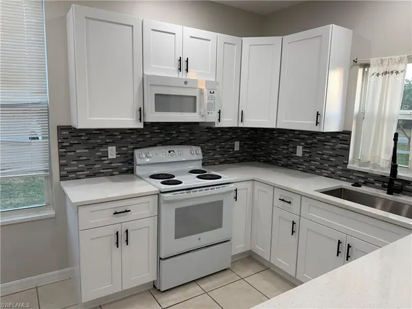 a kitchen with white cabinets and white appliances