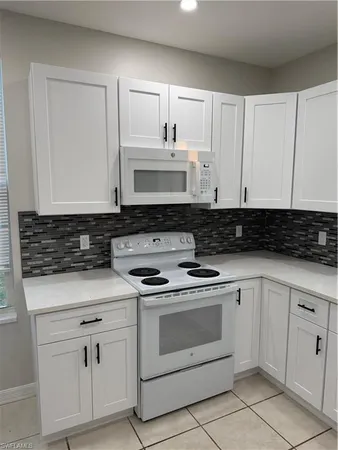 a kitchen with white cabinets and white appliances