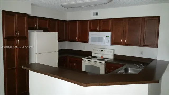 a kitchen with granite countertop stainless steel appliances a refrigerator a stove top oven and cabinets