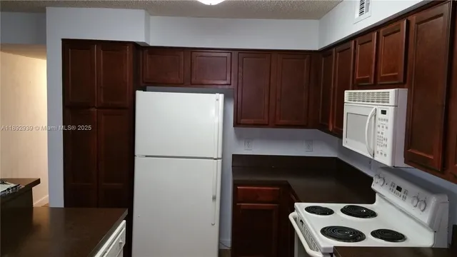 a view of kitchen with cabinets and refrigerator