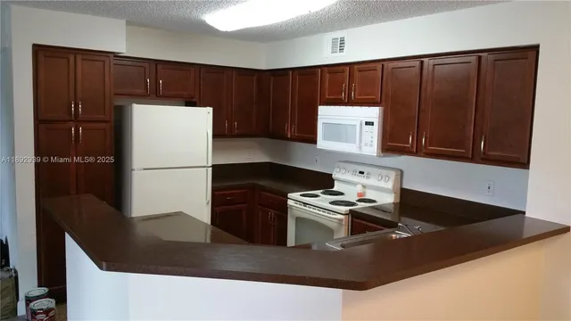 a kitchen with granite countertop a refrigerator a stove and a sink