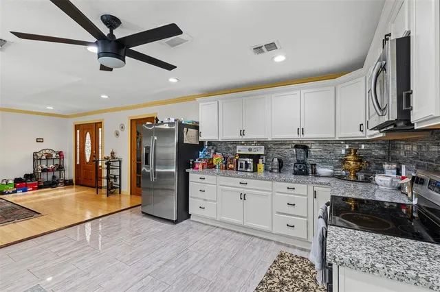 a kitchen with stainless steel appliances granite countertop a refrigerator a stove and white cabinets with wooden floor