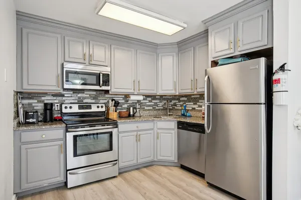 a kitchen with cabinets stainless steel appliances and wooden floor