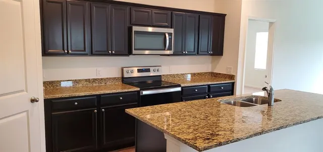 a kitchen with stainless steel appliances granite countertop a refrigerator a stove and a sink