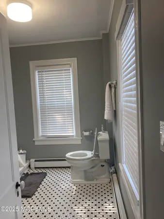 a bathroom with a sink a toilet a window and a mirror