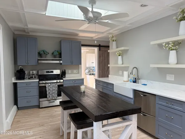a kitchen with a stove a sink dishwasher a kitchen island with wooden cabinets and floor