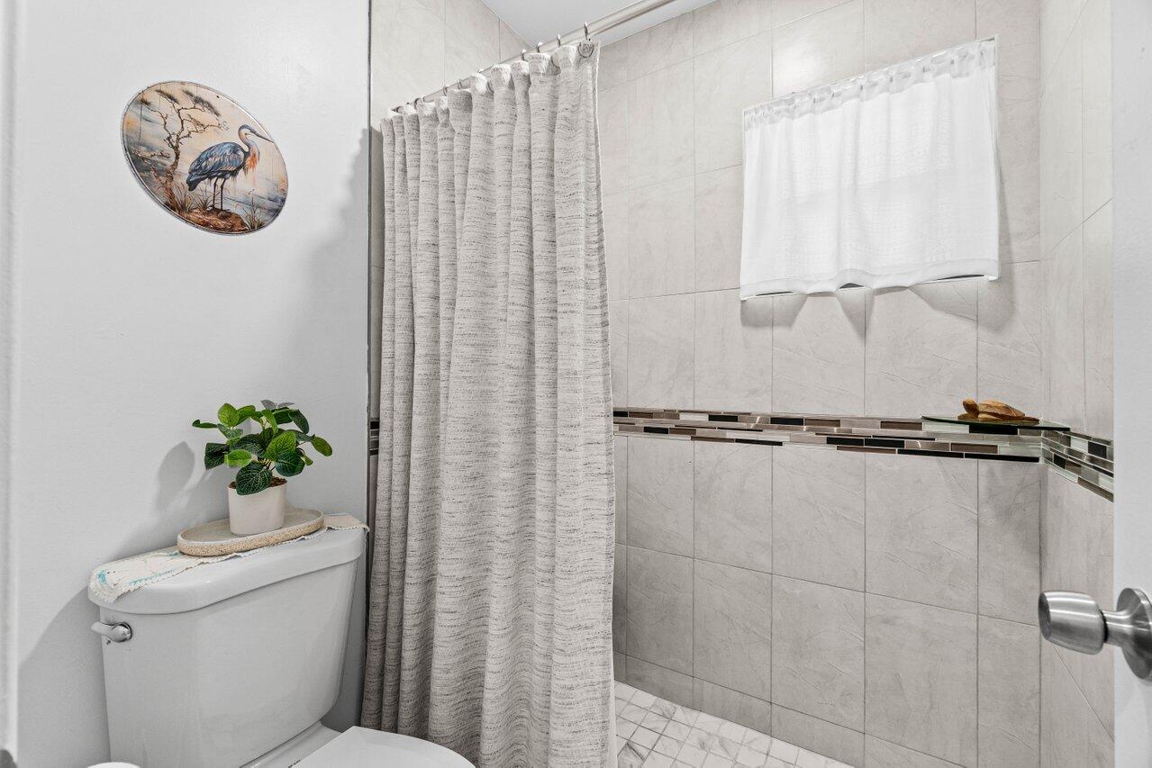 4260 Mango Tree Court, Unit B Boynton Beach, FL 33436 - Photo 15 of 35 a bathroom with a toilet sink and shower curtain