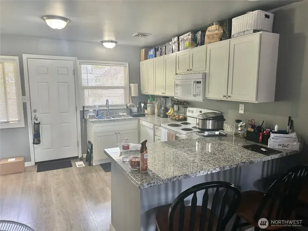 a kitchen with granite countertop a stove a sink and cabinets