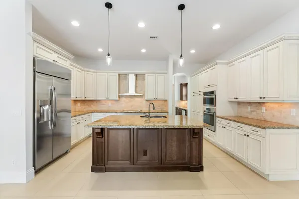 a kitchen with granite countertop kitchen island stainless steel appliances a sink and a wooden floors