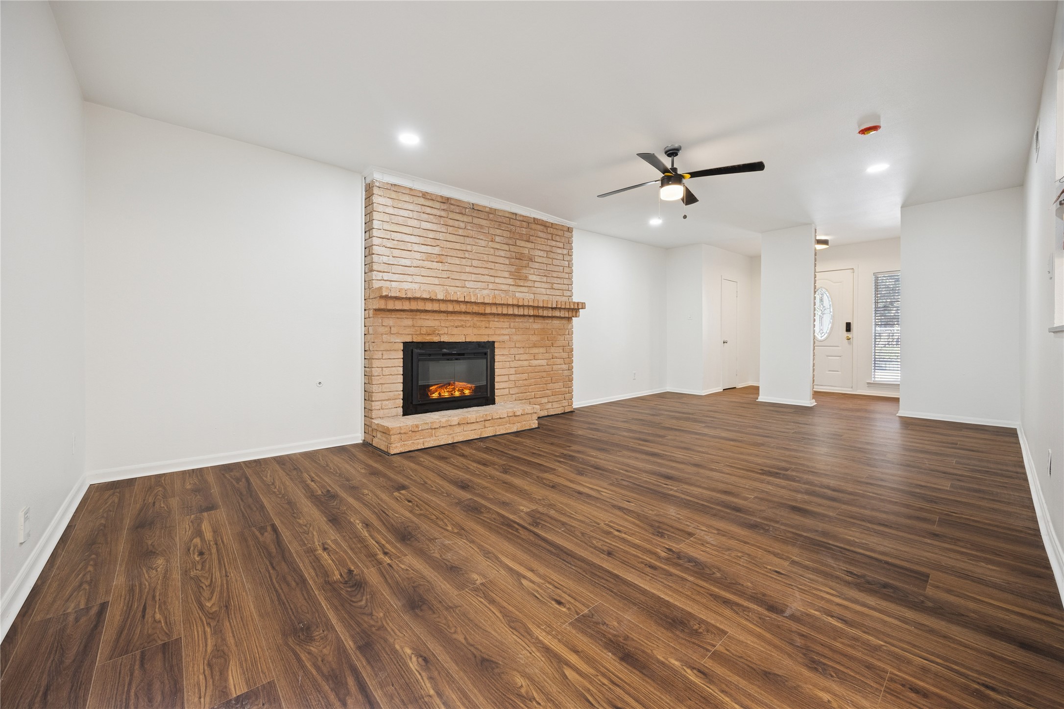 705 Harold Street, Unit 2 Houston, TX 77006 - Photo 2 of 15 an empty room with wooden floor a ceiling fan a fireplace and windows