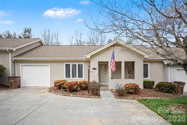 a view of a white house with a outdoor space and a tree