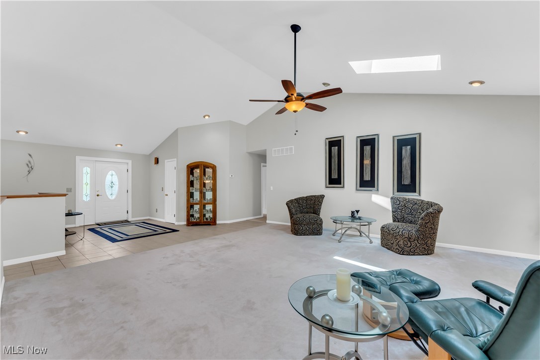 8651 State Road North Royalton, OH 44133 - Photo 6 of 33 Living area featuring light colored carpet, a skylight, a ceiling fan, high vaulted ceiling, and light tile patterned floors