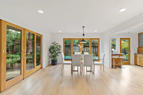 a view of a kitchen with kitchen island stainless steel appliances wooden floor dining table and chairs