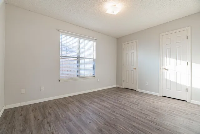 an empty room with wooden floor and windows