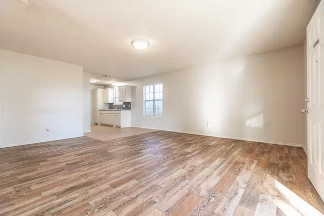 a view of empty room with wooden floor and window