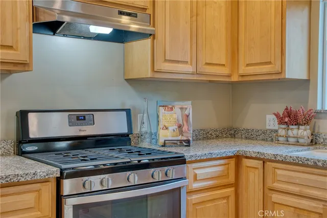 a kitchen with granite countertop stainless steel appliances stove top oven and cabinets