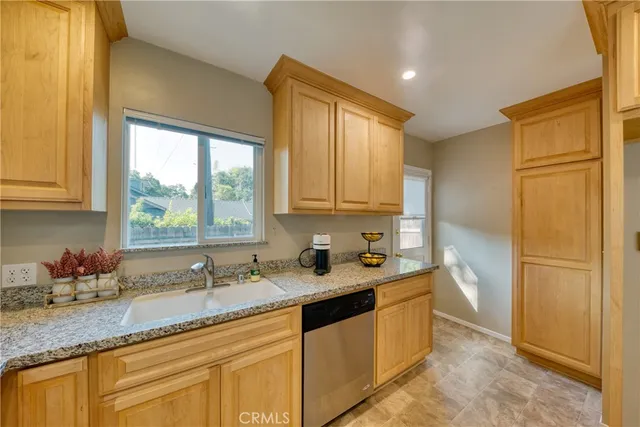 a kitchen with granite countertop stainless steel appliances a sink window and cabinets