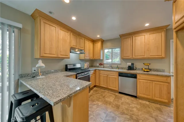 a kitchen with granite countertop kitchen island stainless steel appliances a sink stove top oven and cabinets