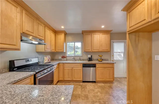 a kitchen with stainless steel appliances granite countertop a stove a sink and a refrigerator