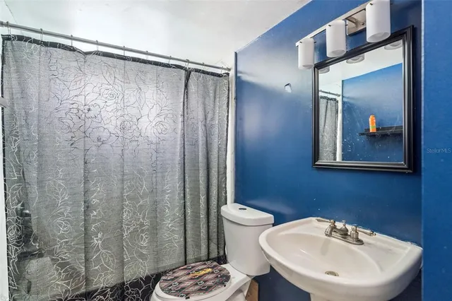 a bathroom with a sink a toilet a mirror and shower curtain
