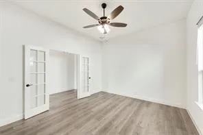 an empty room with wooden floor and ceiling fan