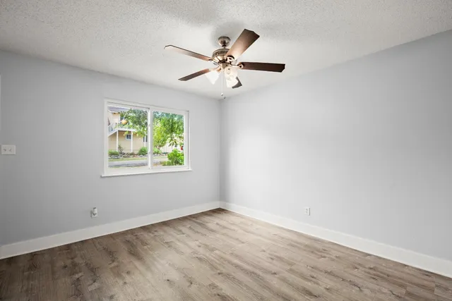 an empty room with window and ceiling fan