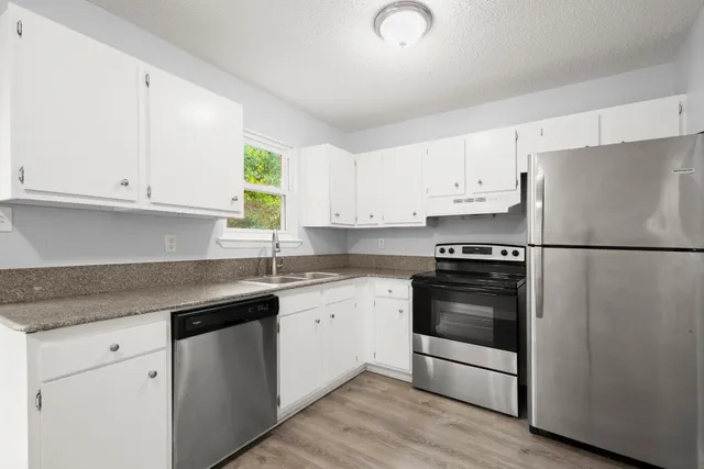 a kitchen with granite countertop white cabinets and stainless steel appliances