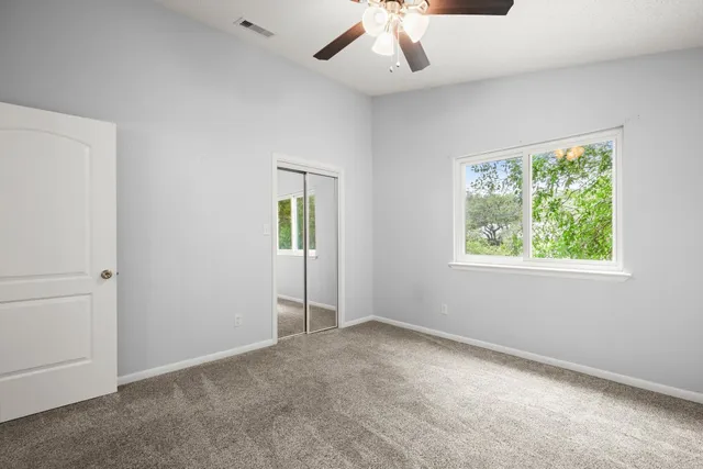 an empty room with a window and a ceiling fan