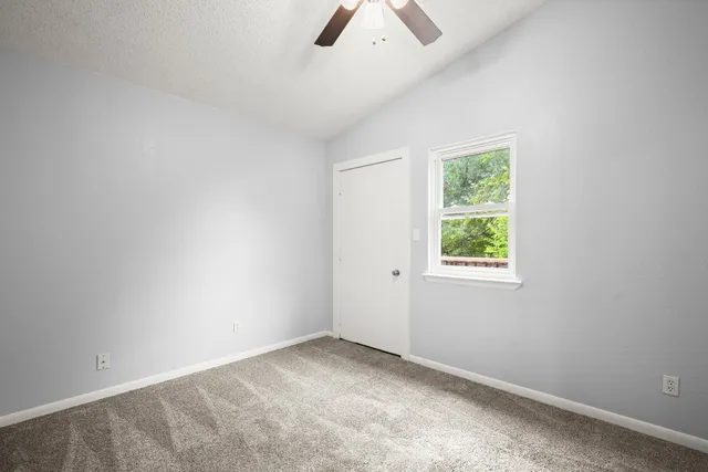 an empty room with ceiling fan and window