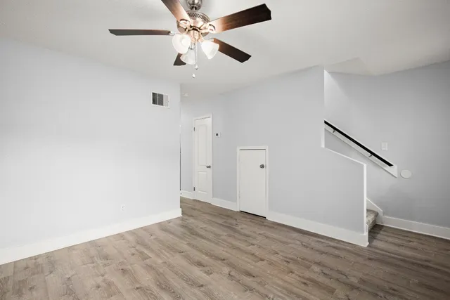 an empty room with wooden floor and ceiling fan