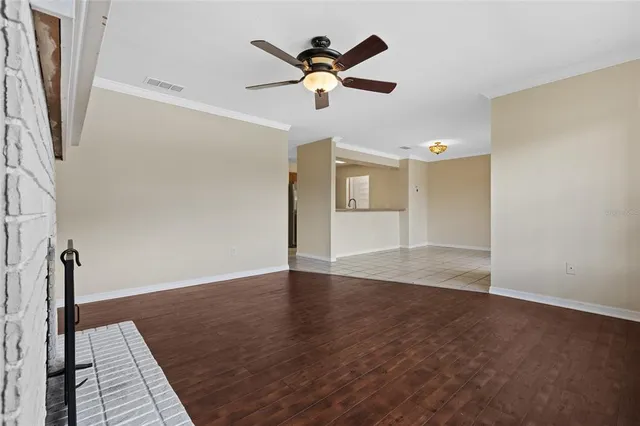 an empty room with wooden floor and ceiling fan