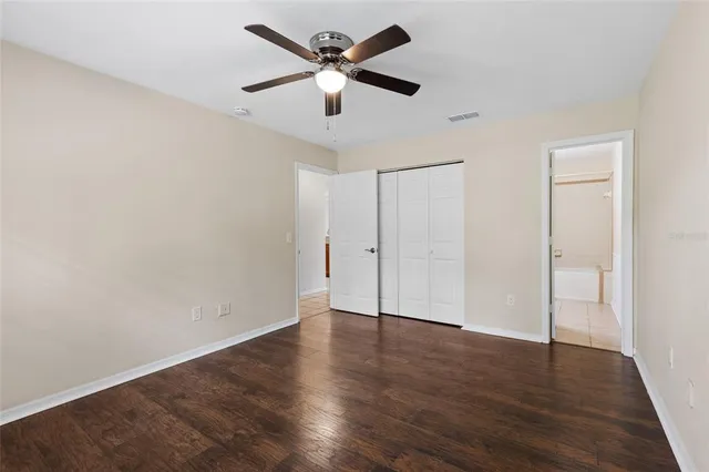 an empty room with wooden floor and ceiling fan